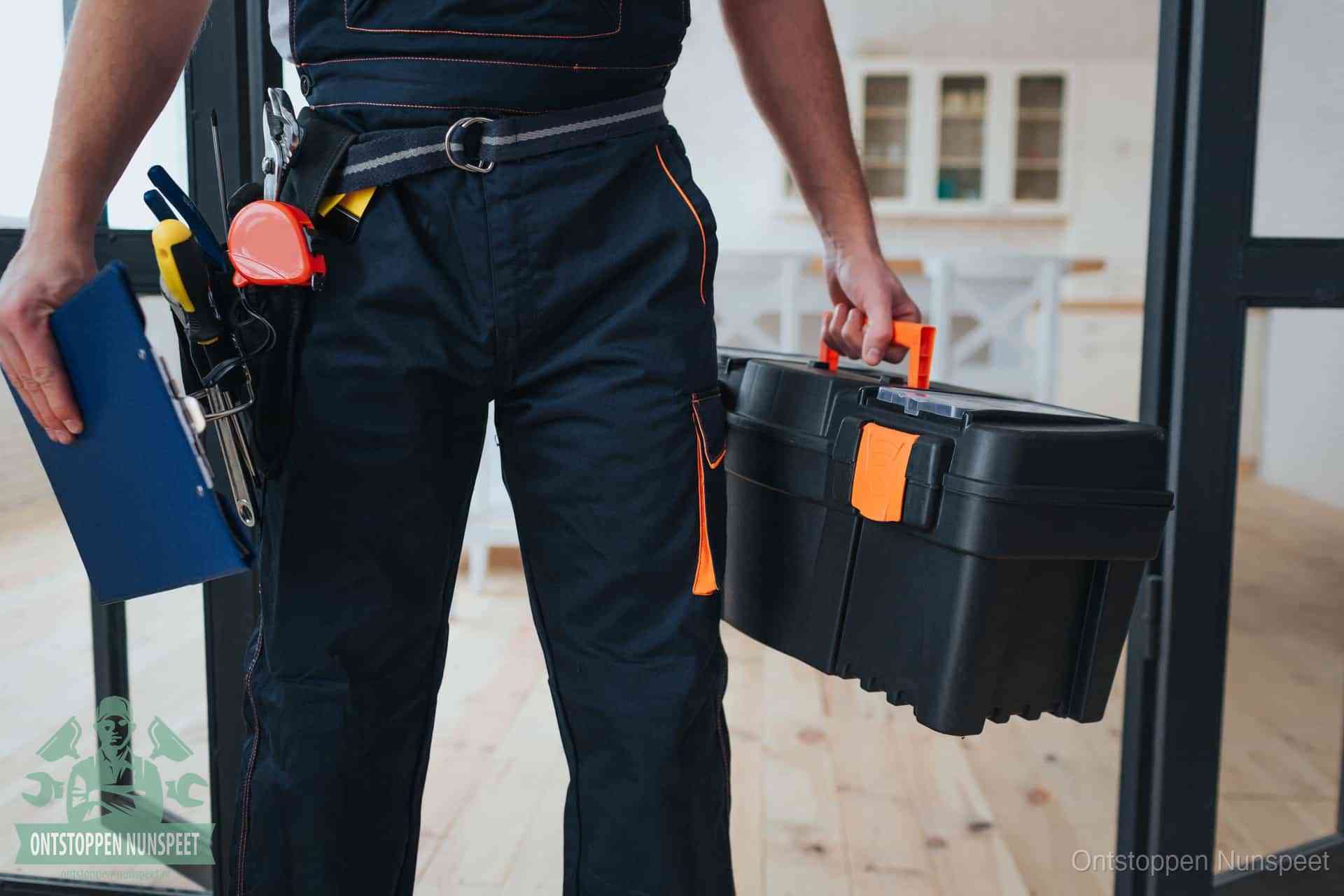 Een monteur met gereedschapsriem en klembord in een keuken, klaar om een transparante prijs voor het gootsteen ontstoppen in Nunspeet te geven