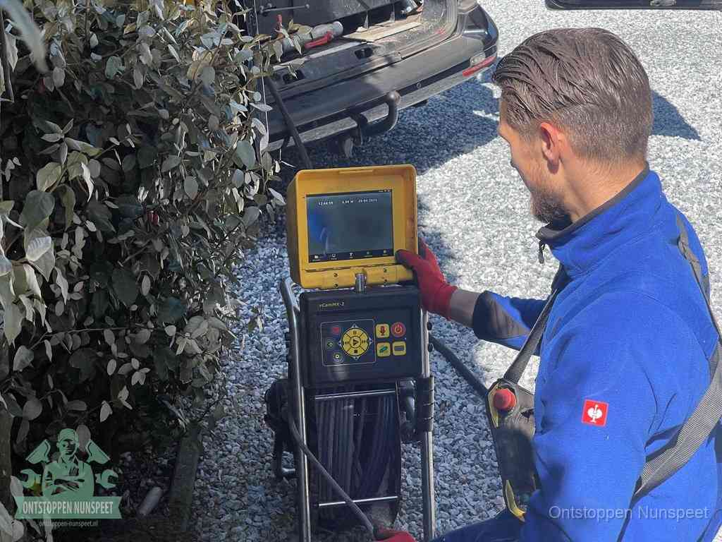 Monteur bedient een rioolinspectiecamera met monitor voor rioolinspectie in Nunspeet