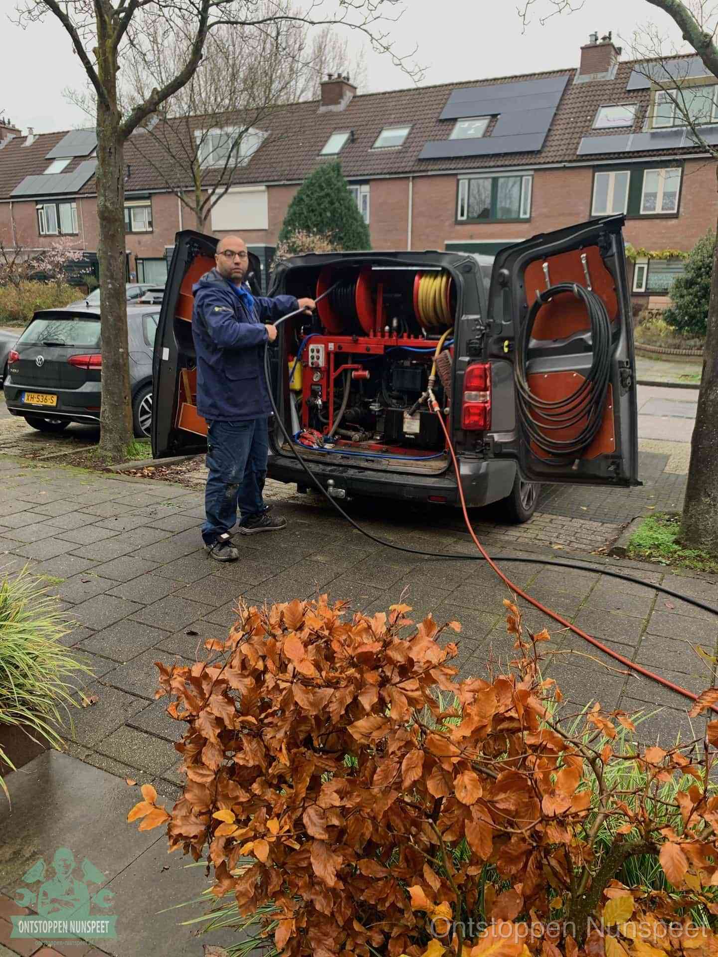 Monteur met rioolreinigingsbus levert rioolservice in de wijk in Nunspeet