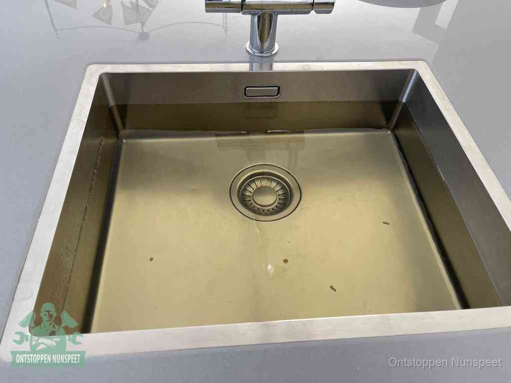 Stilstaand water in een rvs spoelbak dat niet wegloopt, een duidelijk signaal van een gootsteenverstopping in Nunspeet