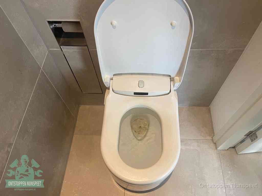 Een wit hangtoilet waarin een prop wc-papier op het water blijft drijven, een duidelijk signaal van een verstopte wc in Nunspeet
