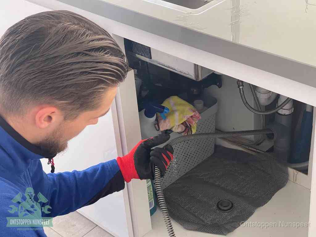 Een monteur voert een flexibele ontstoppingsveer in de afvoer om een verstopping voorbij de bocht van het toilet te bereiken in Nunspeet