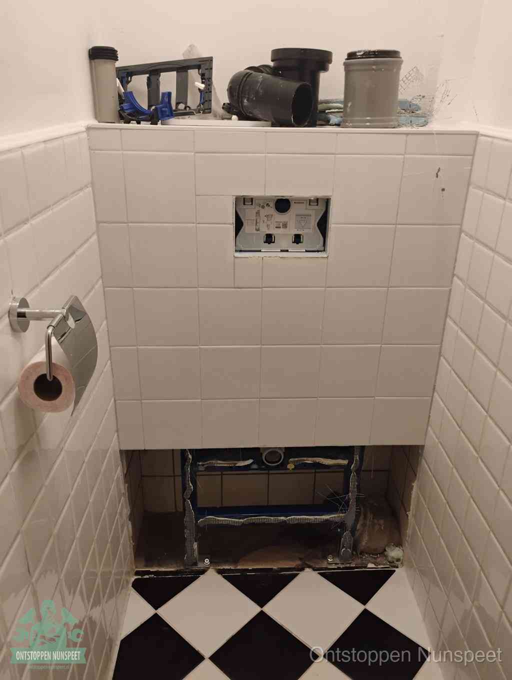 Een toiletruimte waar het hangtoilet en de inbouwreservoir-onderdelen zijn vrijgelegd voor onderhoud, periodiek nazicht voorkomt een wc-verstopping in Nunspeet